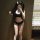 Woman wearing black lace trim crop top and high-waisted shorts set with white thigh-high stockings, sporty chic look.