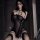 Woman wearing black sheer lingerie set with fishnet stockings and elegant straps, playful bedroom sleepwear for couples.