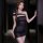 Woman wearing black off-shoulder sensual lingerie dress with sheer fabric and side slit, posing in dimly lit hallway.