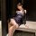 Woman wearing blue lace lingerie set with fishnet stockings, seated on bench in elegant room.