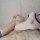Woman wearing white open-crotch bodysuit with blue trim, lying on fluffy rug — sensual pure-yu inspired lingerie set for adul...