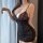 Woman wearing black lace chemise with pearl chain detail, sheer fabric and ruched skirt. sensual qqny sleepwear for couples.
