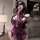 Woman wearing sensual purple lace bodysuit with open-crotch design, long gloves, and blindfold in modern room.