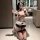 Woman kneeling in bathroom wearing sensual role play lingerie set with headband, wristbands, and anklets.