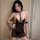 Woman wearing sensual sheer lace lingerie set with transparent mesh bra, panty, and gold chain details.