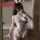 Woman in mirror wearing white sheer mesh bunny costume with open-crotch, cut-out bust, ruffles, and lace-up front.