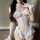 Woman modeling white sheer mesh bunny lingerie set with open-crotch, cut-out bust, ruffles and lace gloves.