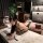 Woman in sexy bunny girl bodysuit with cut-outs and sheer mesh, posing provocatively on a marble countertop in a modern room.