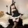 Woman wearing black bunny lingerie set with sheer dress, adjustable straps, and lace details, posing playfully on a couch.