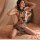 Woman wearing sheer butterfly lace cheongsam sleepwear with floral embroidery, posing on bed in sensual lingerie outfit.