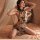 Woman wearing sheer butterfly lace cheongsam sleepwear with floral embroidery, posing on bed in sensual lingerie outfit.