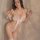 Woman wearing a seductive pink lingerie set with feather details and an open-crotch design, perfect for role play.