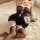 Woman wearing black lace catwoman lingerie dress with sheer bodice, white trim, and matching stockings on bed.