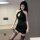 Woman wearing a sexy deep v-neck bodycon mini dress with sheer stockings, posing in a modern room.