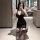 Woman in black deep v-neck bodycon mini dress with sheer striped stockings, posing in modern bathroom mirror selfie.