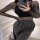 Woman wearing a black fishnet bodysuit with long sleeves, paired with dark sweatpants, taking a mirror selfie.
