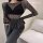 Woman modeling black fishnet bodysuit with long sleeves, paired with gray lounge pants. sexy lingerie set for intimate nights...