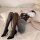 Woman in sexy flight attendant costume lingerie set with black stockings and heels, posing seductively on bed for role play.