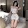 Woman in white sheer lingerie set with lace trim, bow headband, and peace sign gesture on sofa.