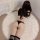 Woman wearing black sheer mesh bodysuit with hip-hugging design, paired with striped thigh-high socks on a fluffy rug.