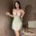 Woman wearing a light green cherry-print babydoll sleep set with red straps and bow, holding a glass; includes built-in pads ...
