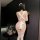 Woman wearing sexy lace backless maid costume with sheer apron, bare-back design, cheeky cutout, and white thigh-high stockin...