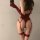 Woman wearing red lace bodysuit with boning and straps, featuring sheer corset top and matching garters for elegant look.