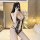 Woman modeling black lace bodysuit with open-crotch design, sheer mesh panels, and seductive cutouts in hotel room setting.