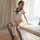 A woman poses elegantly in a white lace bodysuit featuring an open-crotch design, styled like a seductive school uniform. she...