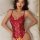 Woman wearing a red sexy lace bodysuit with an open-crotch design, lying on a bed.