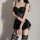 Woman modeling black lace bodysuit set with sheer mesh chemise, matching thong, and gartered stockings for date night.