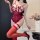 Woman wearing red lace bodysuit with bows, thigh-high stockings, and heels; provocative plus-size lingerie for small bust.