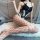 Woman wearing sexy lace bodysuit with ties, sheer panels, and fishnet stockings on white rug.