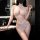 Woman in bathroom wearing white lace bodysuit with sheer mesh panels and hook-and-loop closure, elegant no-remove lingerie.