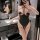 Woman wearing a sexy lace bodysuit with open-crotch design, posing in a modern bathroom.