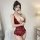 Woman modeling a red lace bodysuit with sheer cut-outs and an open-crotch design, featuring delicate floral patterns and a se...