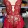 Red sheer lace bodysuit with floral embroidery and scalloped edges, displayed on mannequin in lingerie workshop setting.