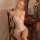 Woman wearing a sexy lace bodysuit with sheer cut-outs, sitting on a vintage chair in a softly lit room.