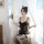 Woman in black lace cat maid corset set with sheer mesh dress, sitting by window holding flowers.
