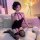 Woman wearing a black lace halter bodycon nightdress with matching garter stockings, posing on a white couch in a softly lit ...