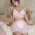 Woman modeling pink and white lace maid lingerie set with sheer mesh skirt, bow details, and contrast trim on bed.