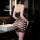 Woman wearing black lace mesh halter dress with open-crotch design, bodycon fit, in modern bathroom setting.
