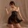 Woman wearing black lace mesh sleepwear set with sheer nightgown and matching bralette, kneeling on bed with soft lighting.