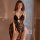 Woman wearing a sexy lace open-crotch bodysuit, sheer seductive sleepwear with intricate floral patterns and elegant design.