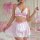 Woman modeling pink and white lace see-through maid costume set with bows, featuring bralette and short skirt.