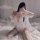 Woman wearing sexy lace sheer sleepwear set with open-crotch bodysuit and robe, posing on bed.