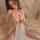 Woman wearing a sexy lace sleep dress with sheer floral front closure, cut-out details, and flirty petal hem on a bed.