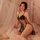 Woman in black lace sleepwear set with sheer mesh cami and skirt, adjustable ties, romantic lingerie nightwear on bed.