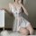 Woman kneeling in white lace sleepwear set with sheer skirt and floral details, showcasing seductive lingerie dress for bedro...