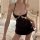 Woman wearing black lace sleepwear slip dress with sheer backless design and delicate mesh detailing in bedroom setting.